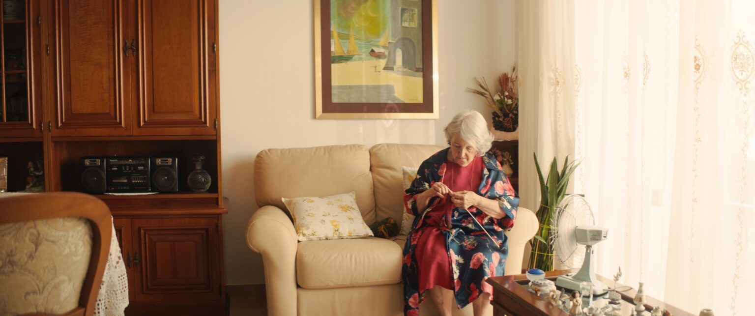 La Truffa, directed by Matteo Stipa and Michele Marchionne: Mirella knits in her armchair, in the sunlit living room