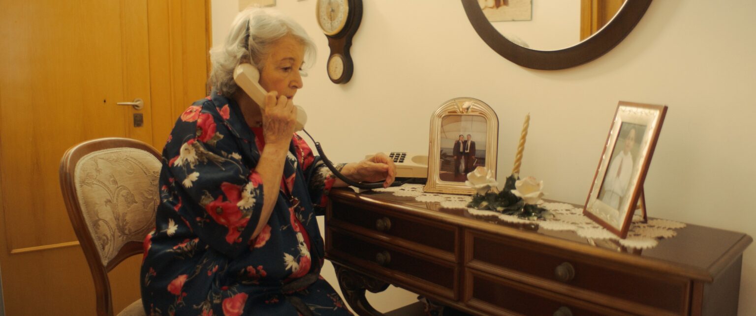 La Truffa, directed by Matteo Stipa and Michele Marchionne: Mirella on the landline, sitting next to the sideboard