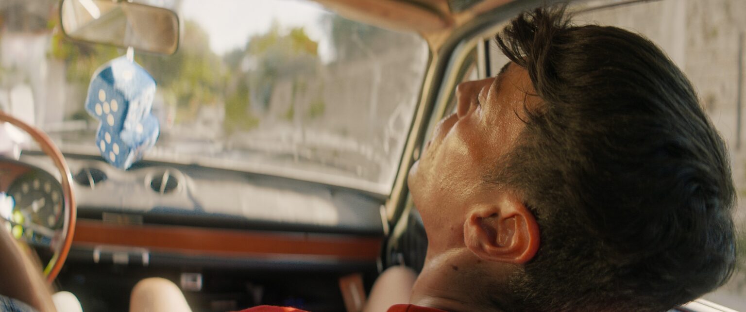 La Truffa, directed by Matteo Stipa and Michele Marchionne: Tommy, in the car, looks up at the rear-view mirror