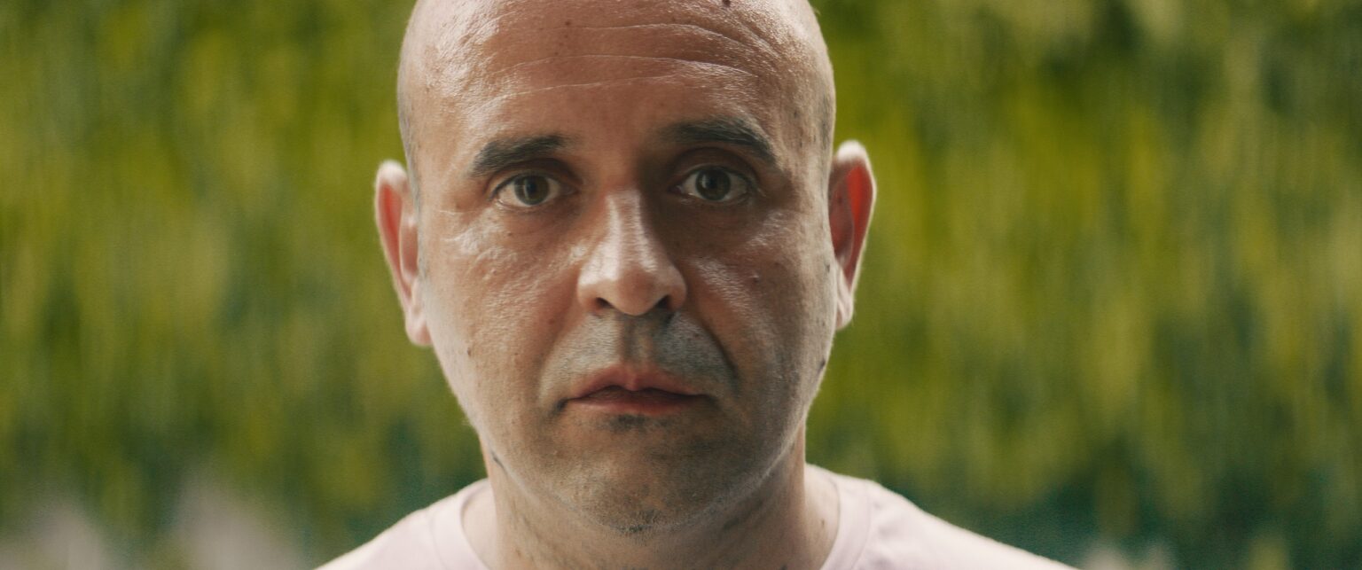 La Truffa, directed by Matteo Stipa and Michele Marchionne: a bald man looks straight into the camera, against the greenery