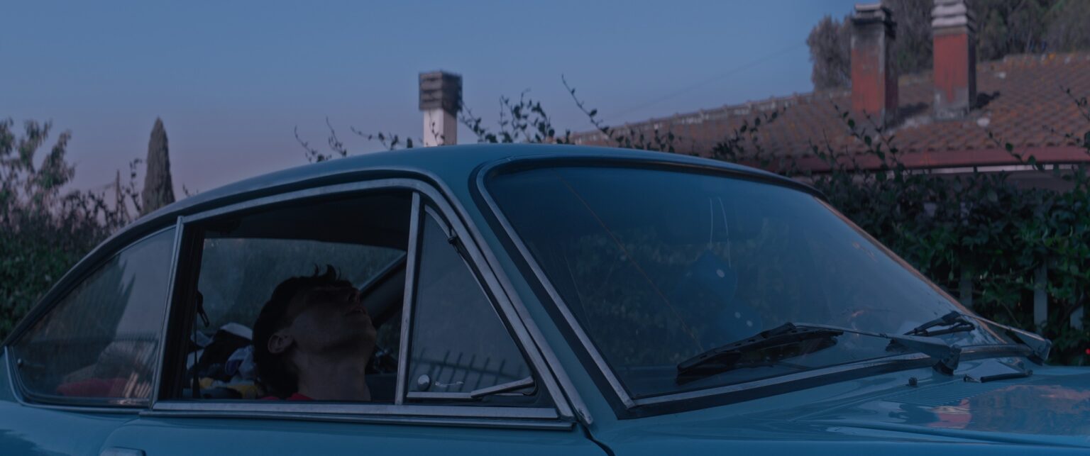 La Truffa, directed by Matteo Stipa and Michele Marchionne: the pale blue vintage car at dusk, with a person inside